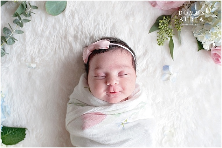 Flowers frame the face of this baby during her newborn session portraits by a houston newborn photographer.