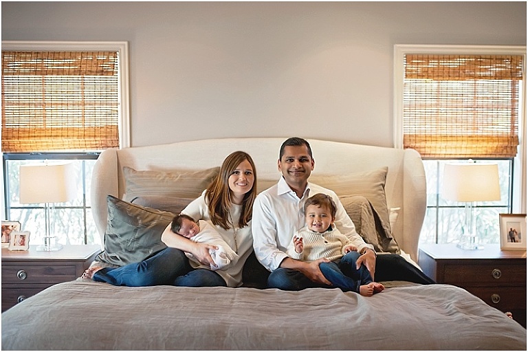 Sweet family sits on their bed together during newborn session in Houston.