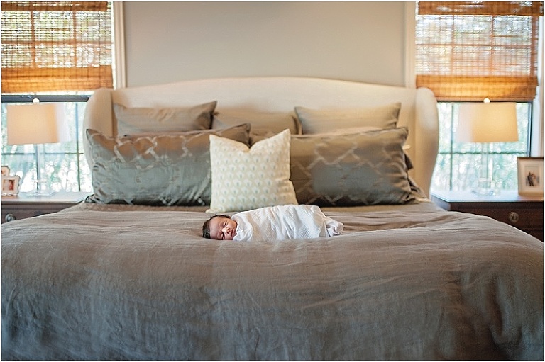 Pullback image of newborn swaddled on bed.