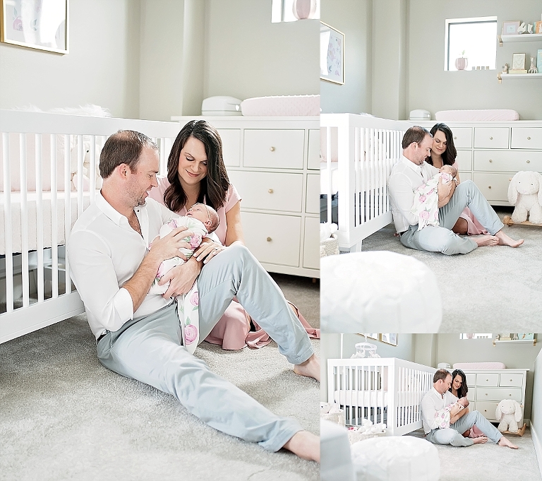 mom and dad hold baby in nursery