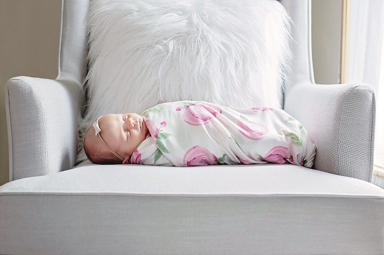 newborn girl lays on rocking chair