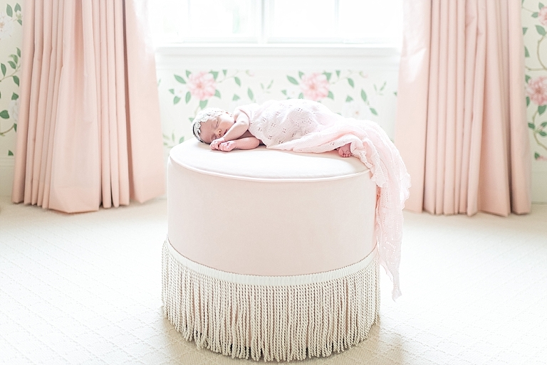 baby girl wrapped in a swaddle lays on pouf